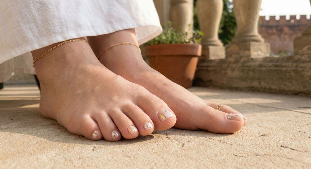 Biżuteryjne paznokcie u stóp na lato z wkomponowanymi akcentami ze złotej i srebrnej folii