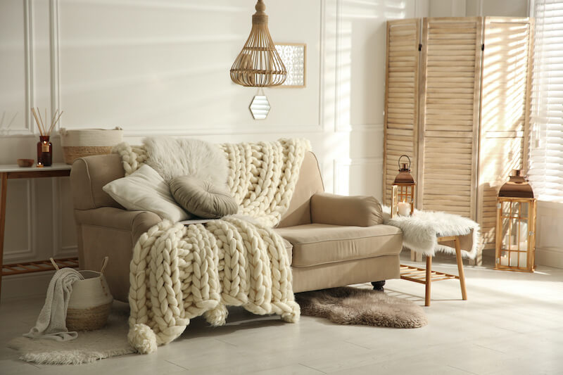 jasny salon w stylu hygge z miękkim kocem i naturalnymi dodatkami